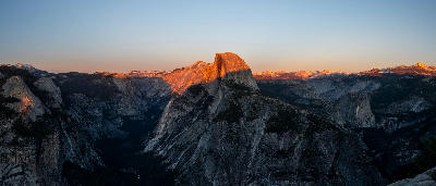 Half Dome glowing in sunset light from Glacier Point with surrounding mountains in Yosemite National Park.
