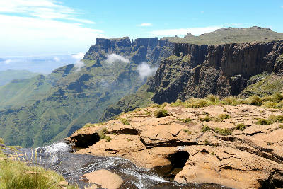 View from the edge of Tugela Falls in the Drakensberg, showing towering cliffs, rugged mountain escarpments, flowing water and deep valleys in KwaZulu-Natal, South Africa.