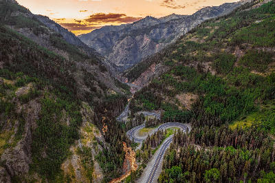Aerial view of a winding mountain road on the Million Dollar Highway near Ouray, Colorado, at sunset.