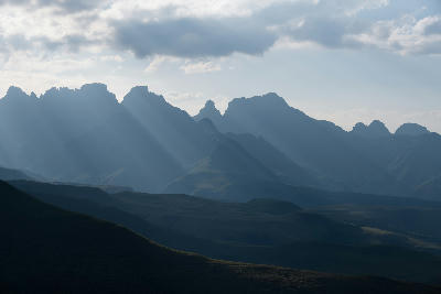 Sunlight breaking through clouds above the rugged Cathedral Peak mountain range in the Drakensberg, South Africa.