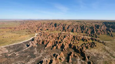 Sweeping aerial view across hundreds of orange-and-black striped sandstone domes and deep valleys of the Bungle Bungle Range.