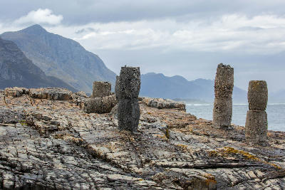 Historic harbour remains and weathered mooring structures on the rocky shoreline of Old Harbour Hermanus, South Africa