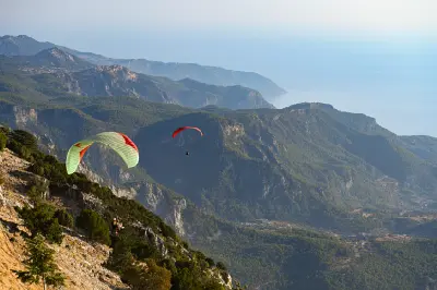 Paragliders flying from Babadağ Mountain above the forested coastal mountains near Ölüdeniz, Turkey.