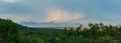 Rainbow and storm clouds above the Waterberg Mountains with bushveld forest and sandstone plateaus stretching across Limpopo, South Africa.