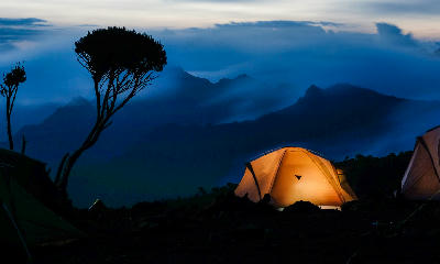 Illuminated tents at Shira Camp on the slopes of Mount Kilimanjaro, Tanzania, at dusk.