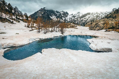 Melting snow and alpine pool beneath rugged peaks in Mercantour National Park, France