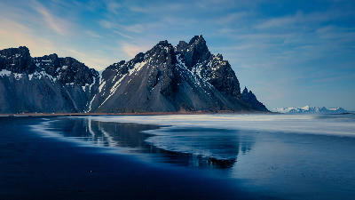Vestrahorn mountain reflected in wet black sand at Stokksnes during winter twilight, southeast Iceland.