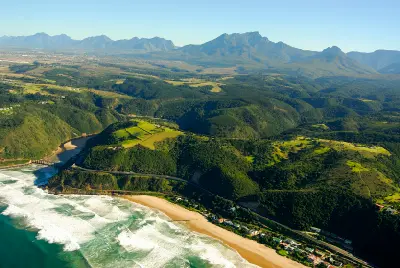 Aerial view of Wilderness on South Africa's Garden Route showing beach, estuary, forested hills and mountain scenery.