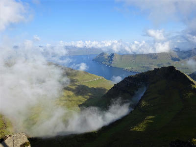 Summit view from Slættaratindur overlooking fjords, green mountain ridges and drifting cloud on Eysturoy, Faroe Islands.