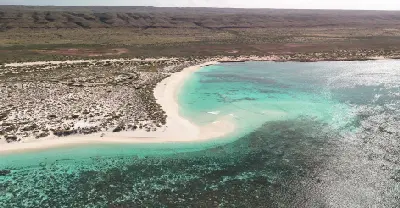 Aerial view of Turquoise Bay with a curved white beach, turquoise water and Ningaloo Reef offshore.