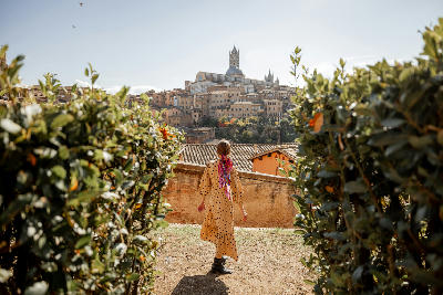 Woman looking toward the historic skyline of Siena with the Siena Cathedral rising above the old town in Tuscany, Italy.