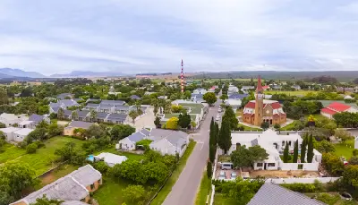 Aerial view of Stanford town with church, tree-lined streets, and surrounding farmland in the Overberg region of the Western Cape, South Africa.