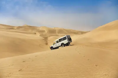 Four-wheel-drive vehicle descending sand dunes in the remote desert landscape of Namibia’s Skeleton Coast.