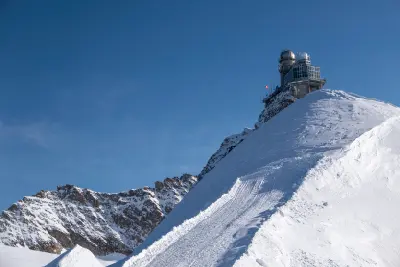 Sphinx Observatory at Jungfraujoch with snow ridge and alpine peaks under clear sky, Bernese Alps, Switzerland.