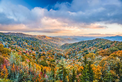 Autumn forest colours across layered mountain ridges at Newfound Gap in Great Smoky Mountains National Park under dramatic clouds at sunset.