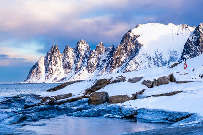 Snow-covered Okshornan peaks above icy coastal rocks at Tungeneset on Senja Island