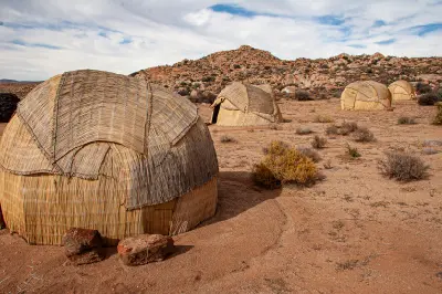 Traditional Khoekhoe matjieshuis reed huts in the Kamiesberg region of Namaqualand, surrounded by rocky hills and semi-arid landscapes in the Northern Cape, South Africa.