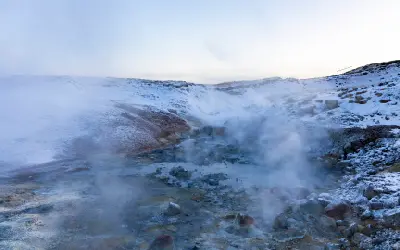Snow-covered geothermal valley with steaming hot pools at the Seltún geothermal area in Krýsuvík on the Reykjanes Peninsula, Iceland.