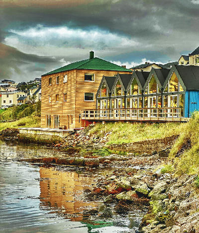 Wooden waterfront buildings reflected in the harbour of Sørvágur on Vágar Island, Faroe Islands.