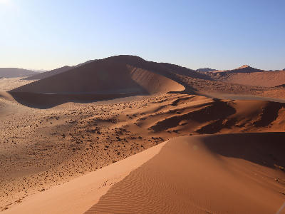 Ridge-top view from Dune 45 across layered red sand dunes in the Sossusvlei region of Namibia.