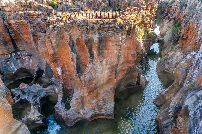 View of Bourke's Luck Potholes showing deep cylindrical rock formations, flowing water and visitor walkways in Mpumalanga, South Africa.