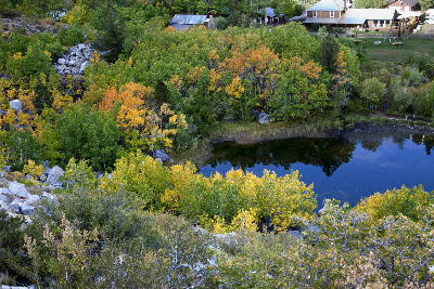 Small pond surrounded by green and yellow aspen trees with nearby cabins in Bishop Creek Canyon, Eastern Sierra Nevada, California