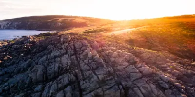 Sunrise illuminating rugged granite formations and coastal heath at Injidup Natural Spa near Yallingup, Western Australia.