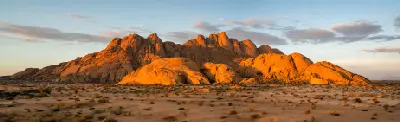 Panoramic view of granite peaks and desert plains at Spitzkoppe in Namibia under warm evening light.