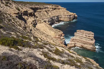 Island Rock rises from the Indian Ocean below the layered coastal cliffs of Kalbarri National Park.