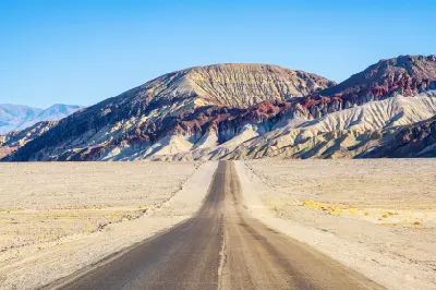 Badwater Road approach to Badwater Basin in Death Valley National Park California with desert valley and colorful eroded hills in background
