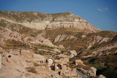 Ancient cave dwellings overlooking Rose Valley from Çavuşin in Cappadocia, Turkey, with layered volcanic cliffs and pink tuff formations in the background.