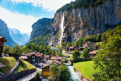 Staubbach Falls towering above Lauterbrunnen village with church, chalets, and river in the valley floor below, Switzerland.