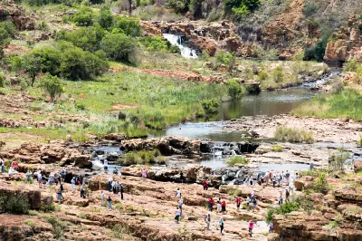 Tourists walking among rock formations and river channels at Bourke's Luck Potholes in Mpumalanga, South Africa.