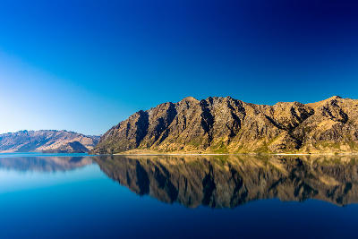 Mountains reflected in the calm water of Lake Hāwea near Wānaka, South Island, New Zealand.