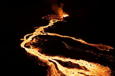 Glowing lava river flowing from an active volcanic vent at Fagradalsfjall on the Reykjanes Peninsula, Iceland, captured at night.