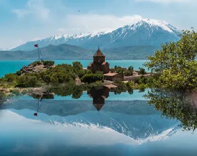 Holy Cross Church on Akdamar Island surrounded by Lake Van with snow-covered mountains rising behind it in eastern Turkey.