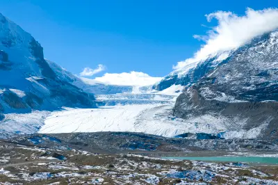 Athabasca Glacier flowing from the Columbia Icefield in Jasper National Park, surrounded by snow-covered mountains and rocky foreground terrain