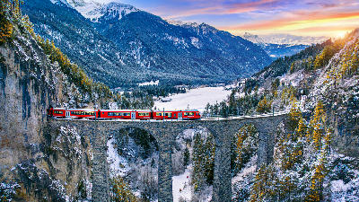 Red train on Landwasser Viaduct above a snowy alpine valley near Filisur, Switzerland