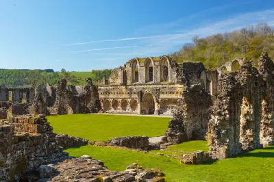 Ground-level view of Rievaulx Abbey's medieval stone ruins, pointed Gothic windows and green lawns in North Yorkshire, England.