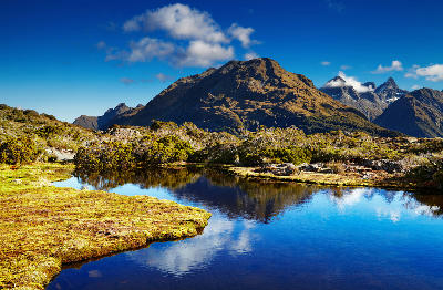Alpine tarn at Key Summit on the Routeburn Track with surrounding mountains reflected in the water, Fiordland National Park, New Zealand.