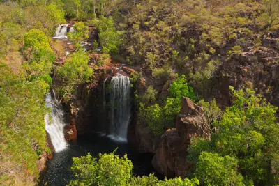 Elevated view of the twin waterfalls at Florence Falls, with upstream cascades, sandstone cliffs and a dark plunge pool surrounded by tropical vegetation in Litchfield National Park, Northern Territory, Australia.