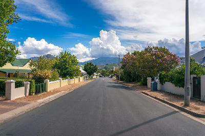 Tree-lined residential street with Cape Dutch homes and mountain backdrop in Franschhoek Village, Western Cape, South Africa.