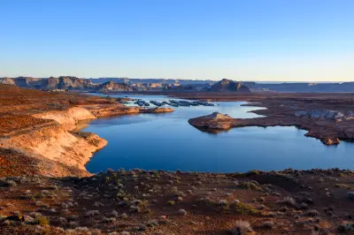 Sunrise view from Wahweap Overlook in Page, Arizona, showing Lake Powell with calm water, marina area, and surrounding sandstone desert landscape.