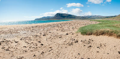 Panoramic view of golden sands and turquoise waters at Rauðasandur Beach in the Westfjords, Iceland.