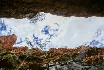 View looking upward between the steep rock walls of Standley Chasm towards the cloudy sky.