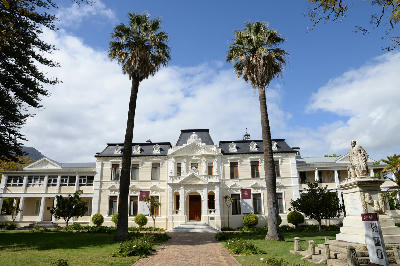 Historic Stellenbosch University campus building framed by palm trees in Stellenbosch, Western Cape, South Africa.
