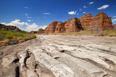 Eroded channels cut through the dry bed of Piccaninny Creek beneath the striped sandstone domes of the Bungle Bungle Range.