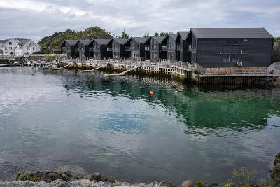 Modern black waterfront cabins on stilts above calm harbour water at Hamn i Senja, Senja