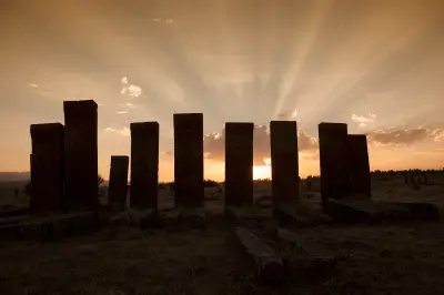 Tall medieval Seljuk tombstones silhouetted against a dramatic sunset at the historic Ahlat cemetery near Lake Van, Turkey.