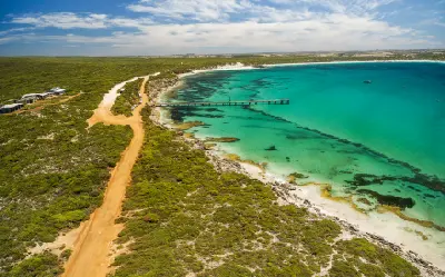 Aerial view of Vivonne Bay jetty, turquoise ocean water, white sandy beach and coastal access road on Kangaroo Island, South Australia.